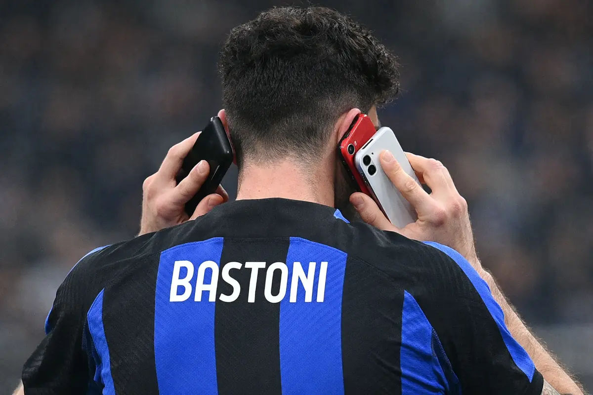 Alessandro Bastoni di spalle con tre telefoni